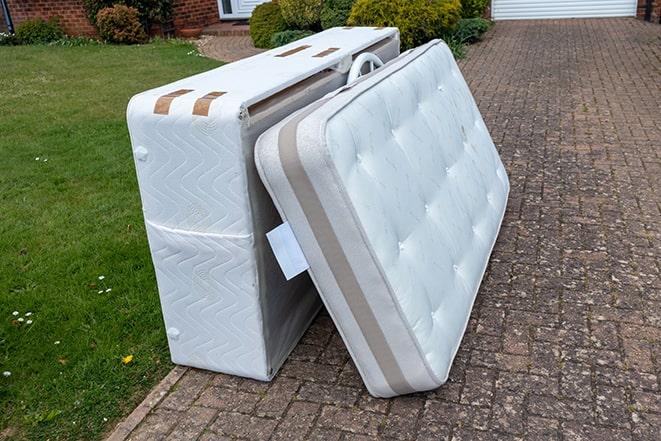 two people lifting a mattress for removal from a residence